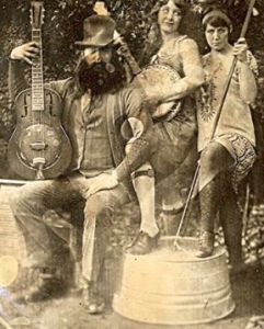 vintage daguerrotype of a man with a mandolin, a woman with a banjo, and another woman with a washtub bass. They are dressed in 1920's clothing.
